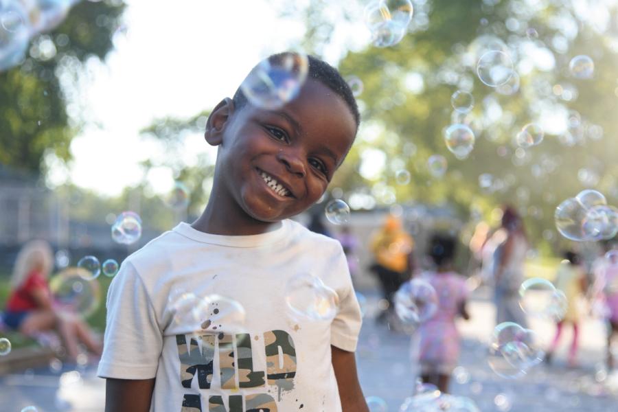 Child at outdoor library event with bubbles